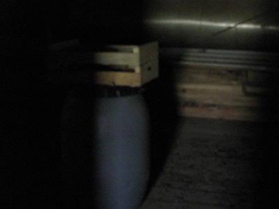 Deux cagettes sur un bidon, à peine visibles dans le noir.